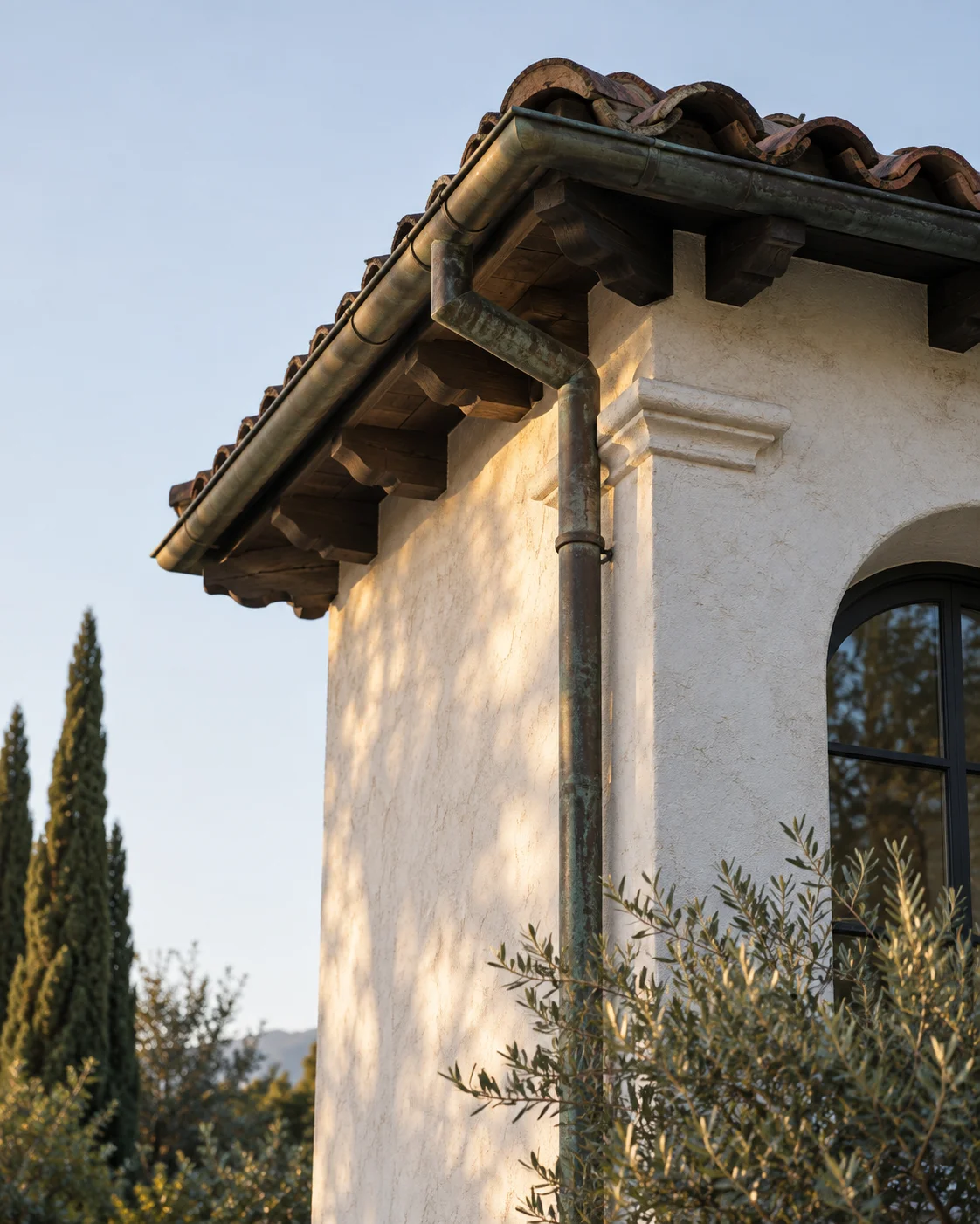 Stucco wall and clay tile eave against a pale sky